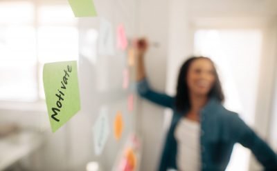 Sticky note with motivate written on it pasted on glass wall